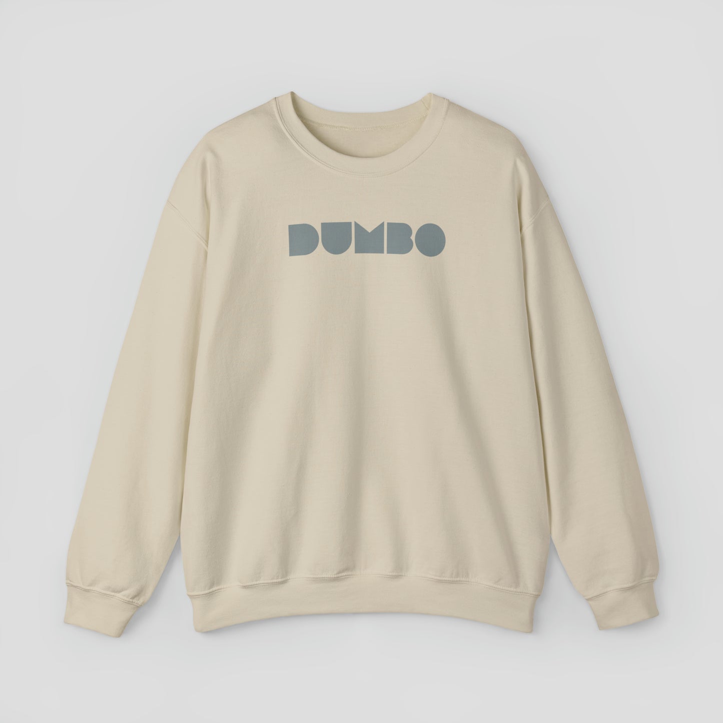 Tan colored sweatshirt with the word Dumbo in gray block letters across the chest, against a gray background.