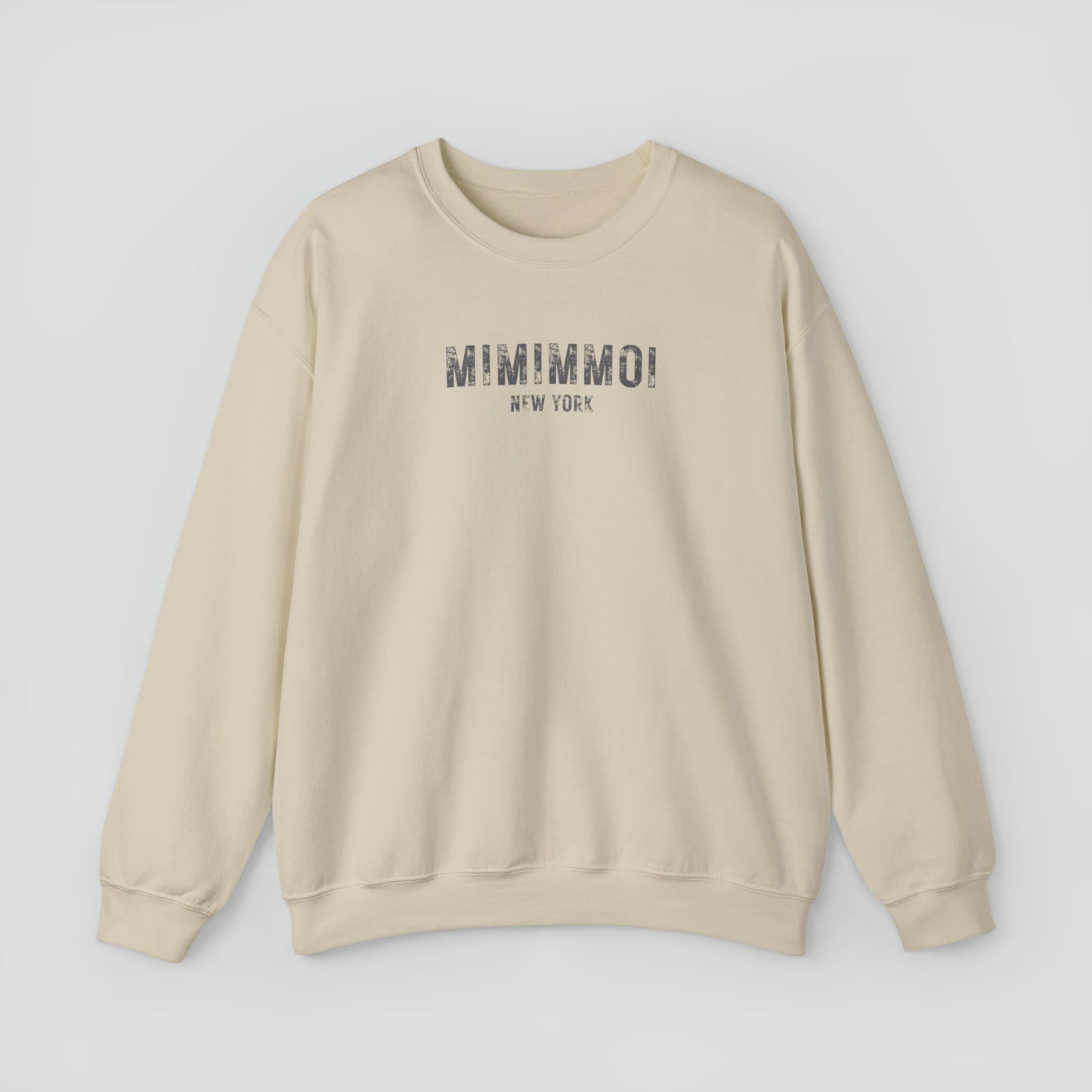 Tan colored sweatshirt with the words Mimimmoi New York in distressed gray block letters across the chest, against a gray background.