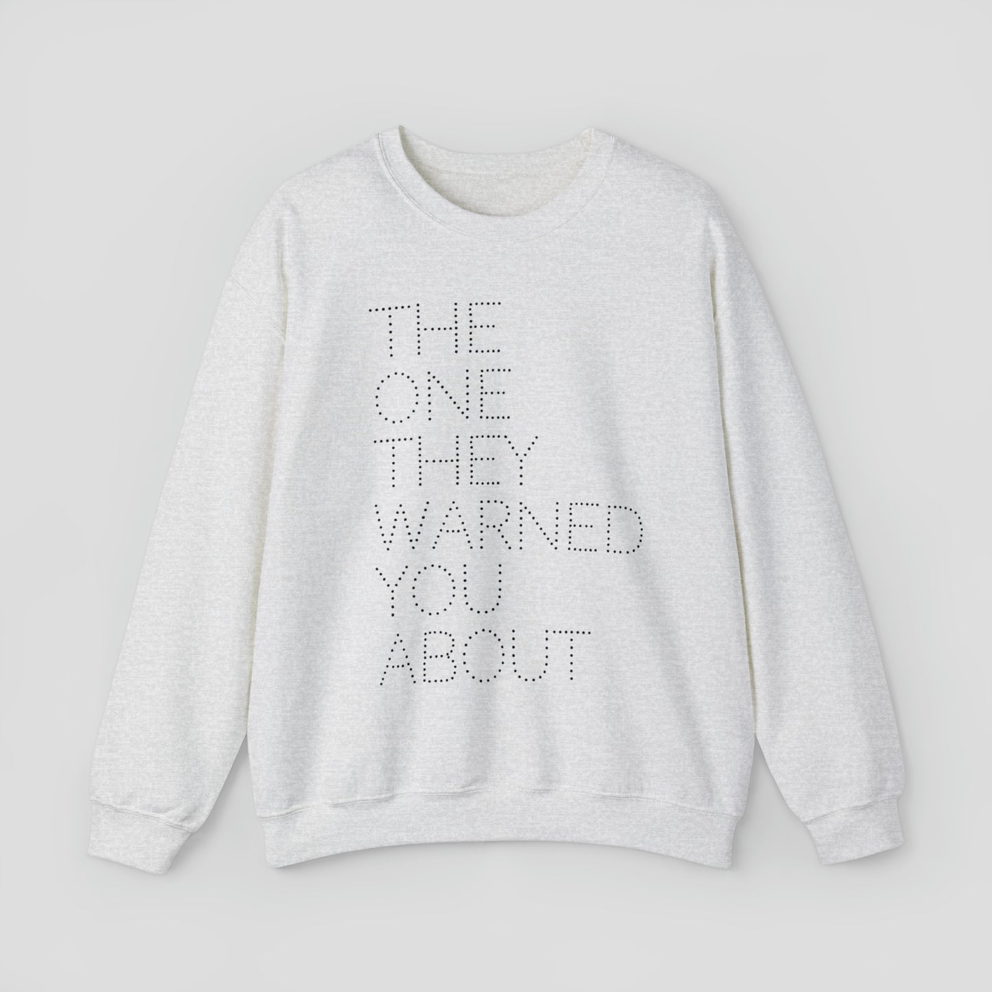Front view of light gray sweatshirt with with the words "The One They Warned You About" in capitalized dotted text in center, against a gray background.
