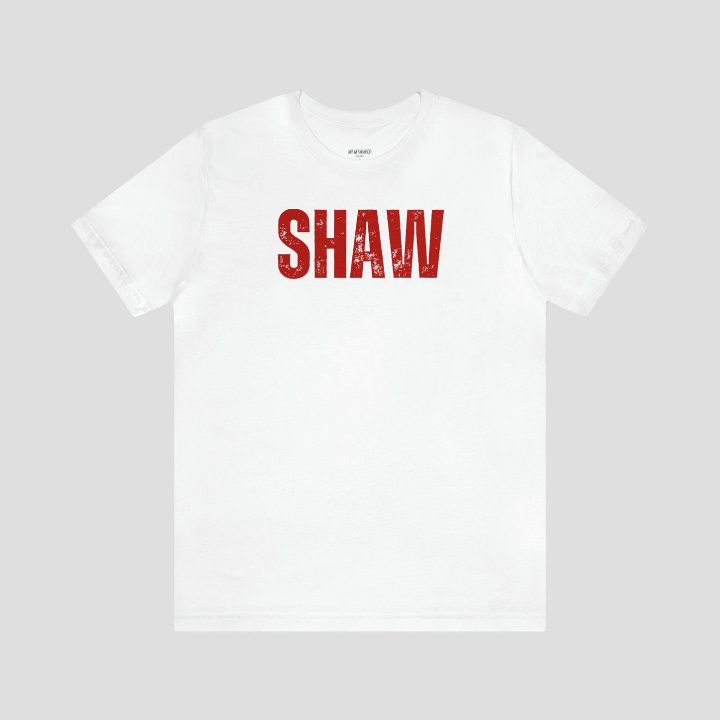 White t-shirt with the word "Shaw" in large red, grunge block letters across the chest, against a gray background.