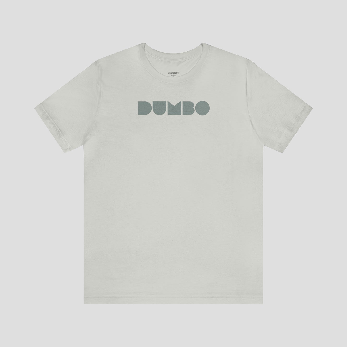 Silver-gray t-shirt with the word Dumbo in gray block letters across the chest, against a gray background.