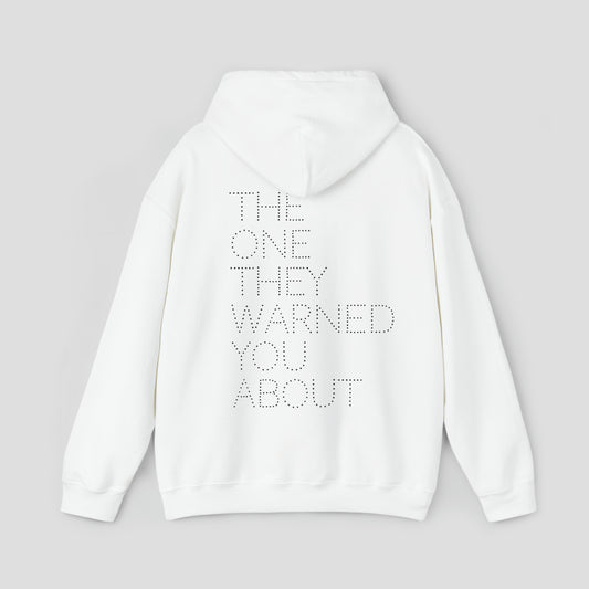 Back view of white hooded sweatshirt with hood down with the words "The One They Warned You About" in capitalized dotted text in center, against a gray background.